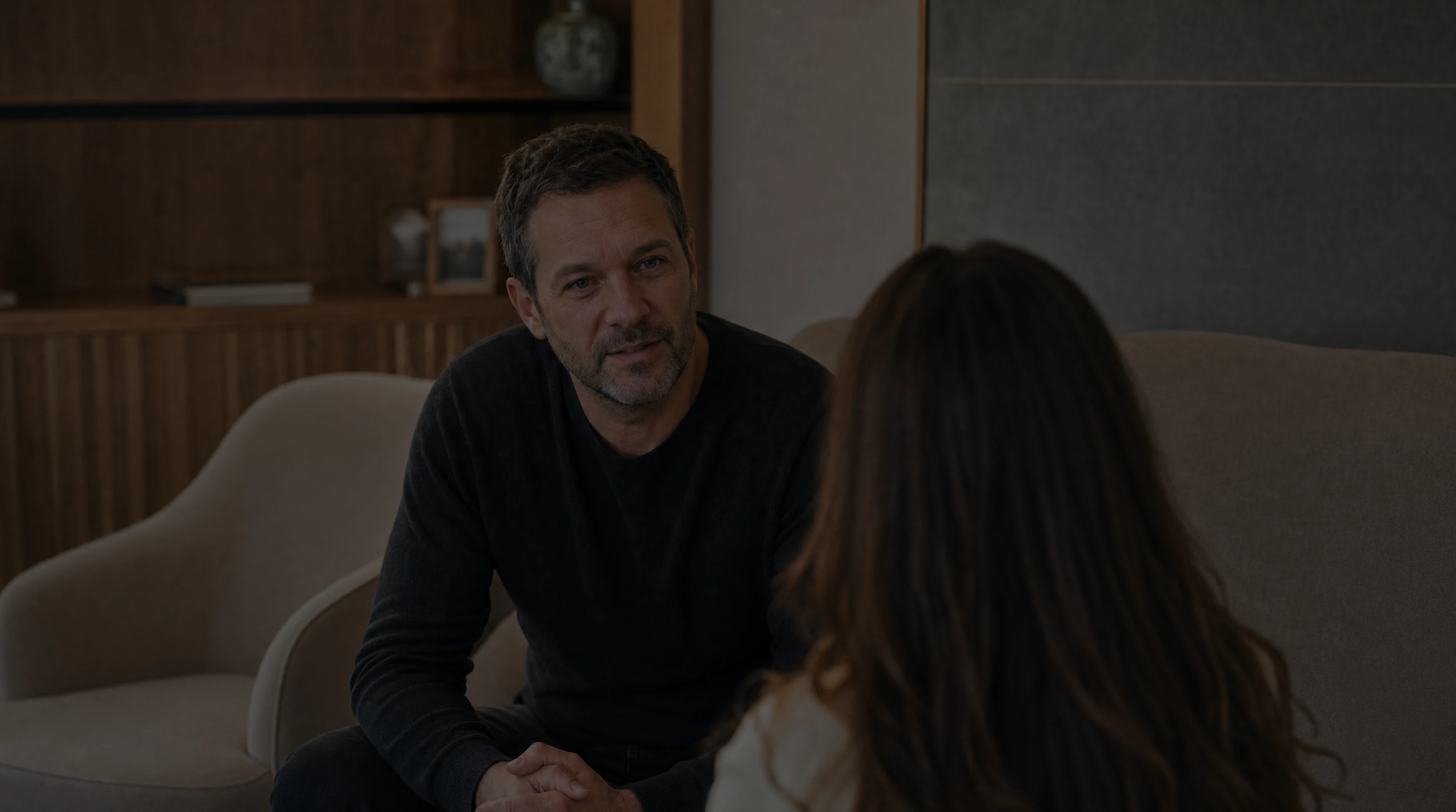 A man listening to a woman during a conversation in a warm modern room.