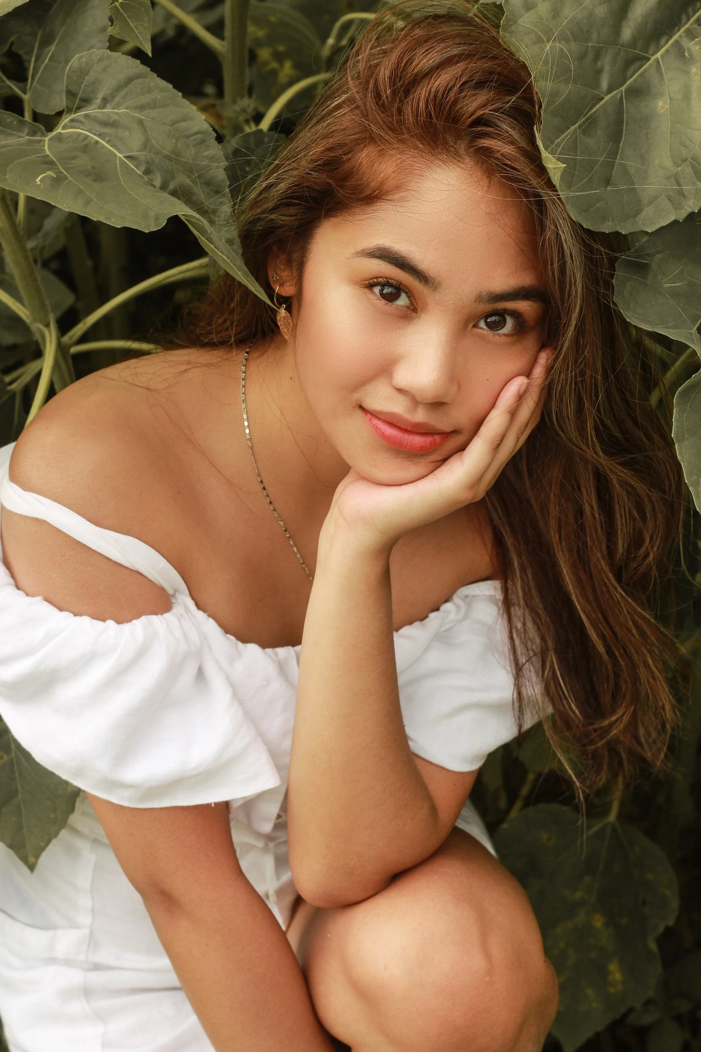 A woman resting beneath broad green leaves