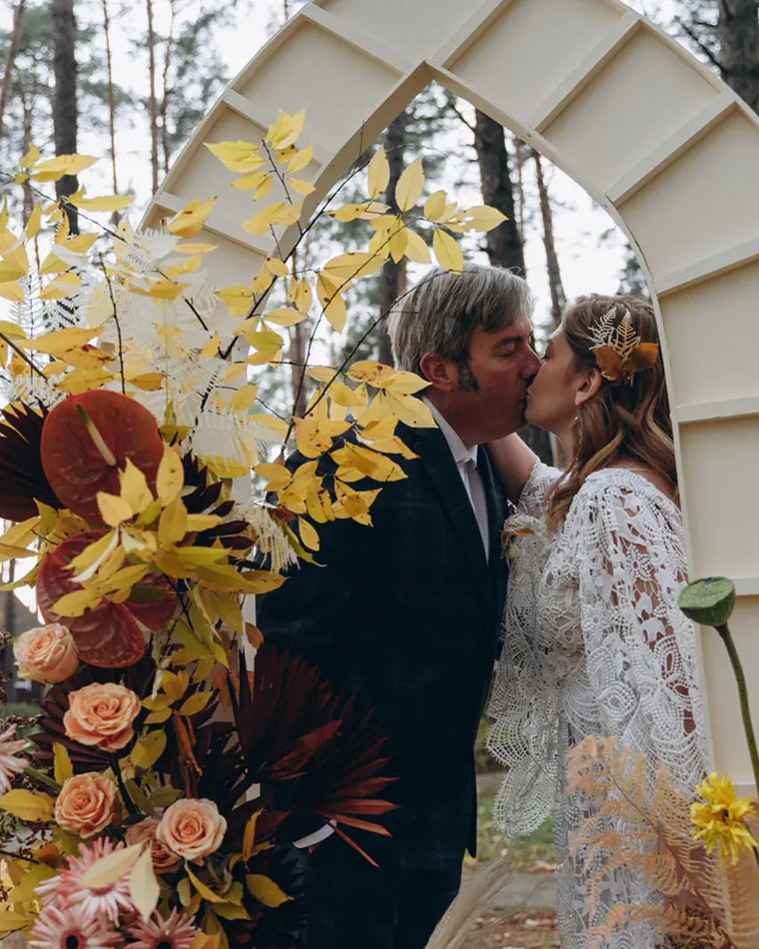William and Lilia sharing a kiss outdoors on their wedding day.